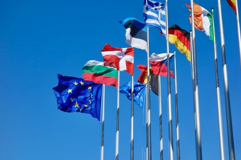 Several EU country flags that are flying in the air
