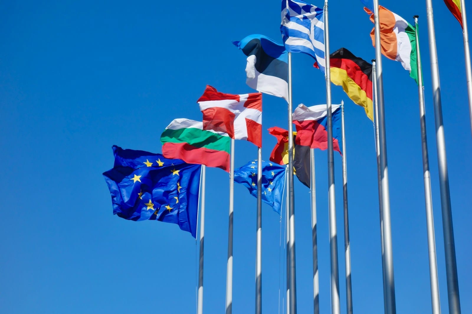 Several EU country flags that are flying in the air