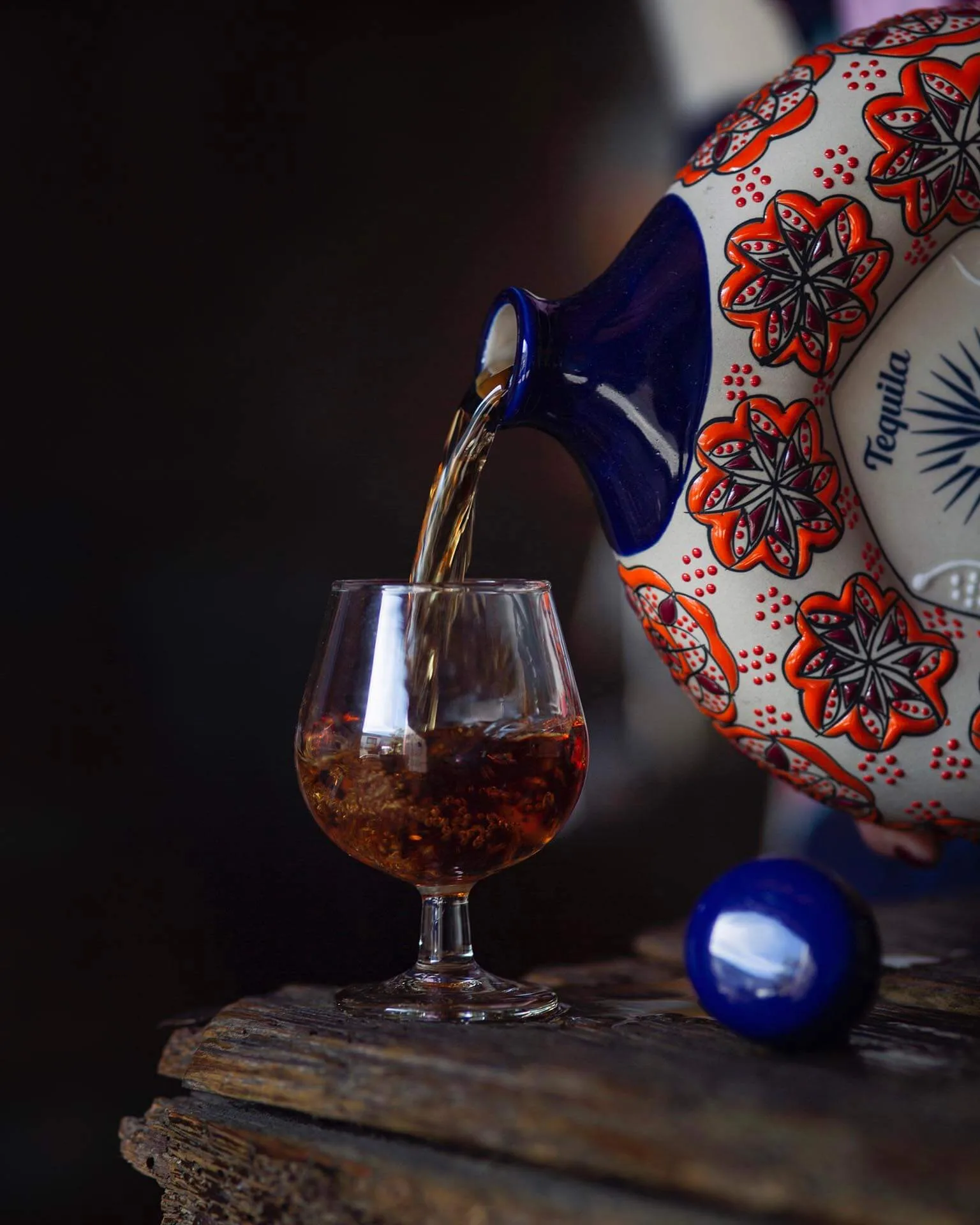 Botella de tequila de colores vertiéndose en un vaso