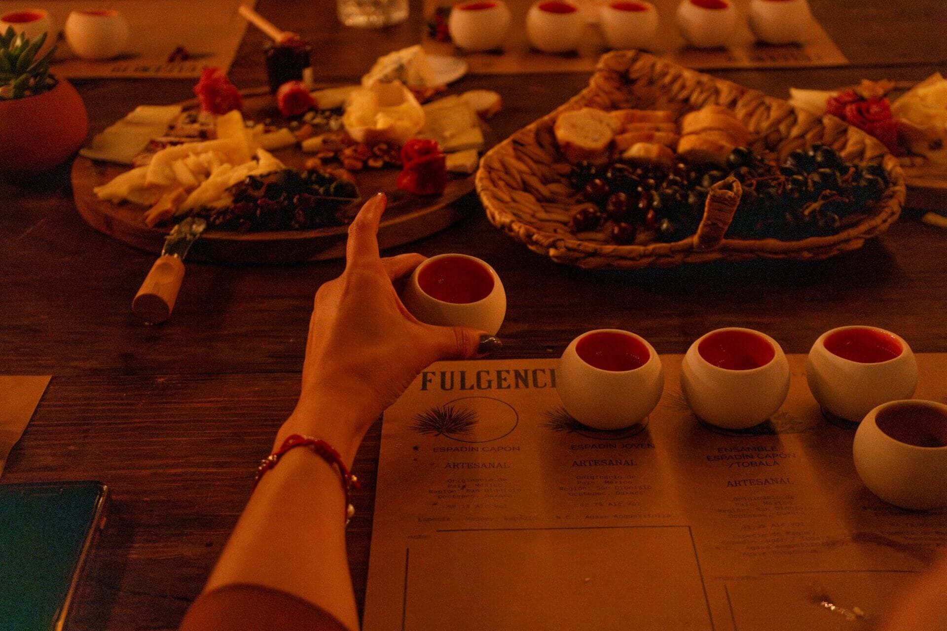 Hand holding mezcal shot at candlelit tasting table