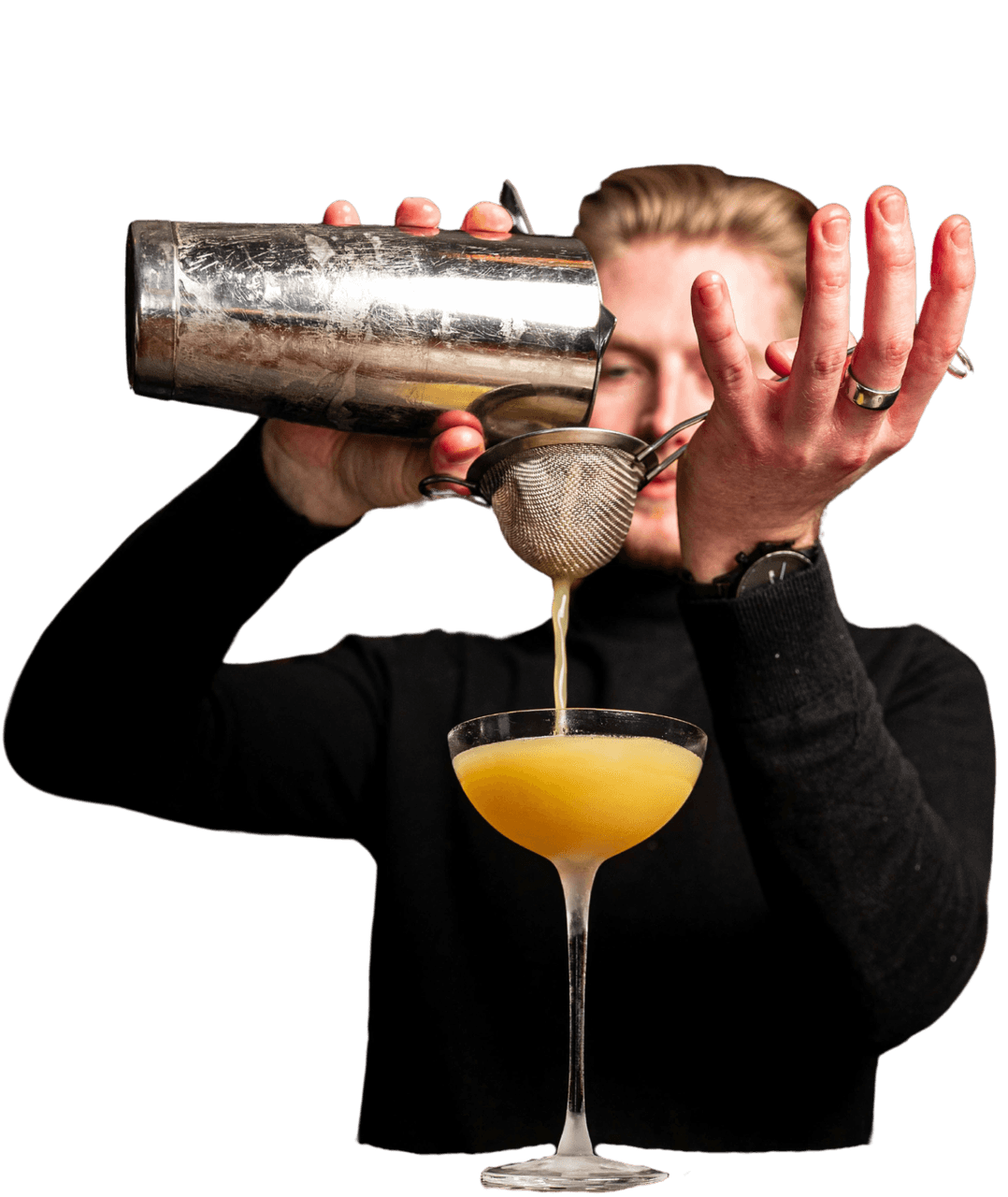 Bartender pouring cocktail through strainer into glass.