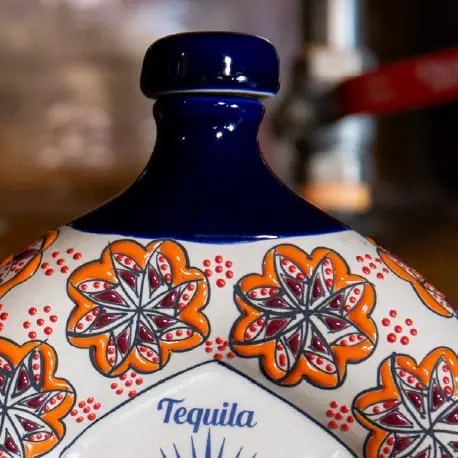 Botella de tequila decorativa con diseño floral.