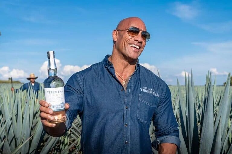 Man holding Teremana tequila bottle in agave field.
