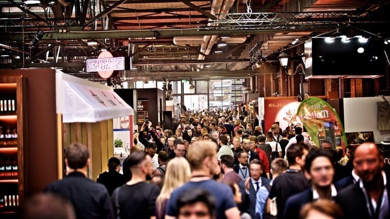 Crowded trade show with various booths and attendees.